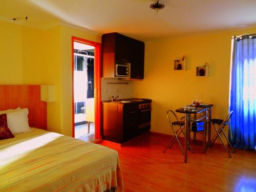 a bedroom with a bed and a table and a kitchen at Norte Guest House in Lisbon
