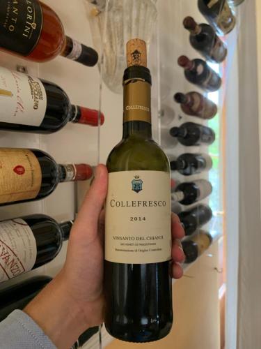 a person holding a bottle of wine in a refrigerator at Hotel Chenno in Subbiano
