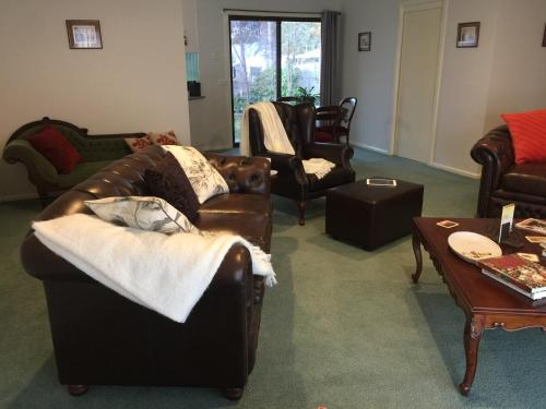 a living room with leather couches and a table at Bird Abode in Maryborough