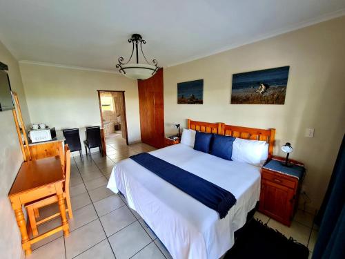 a bedroom with a large bed and a desk at Resthaven Guesthouse in Matatiele