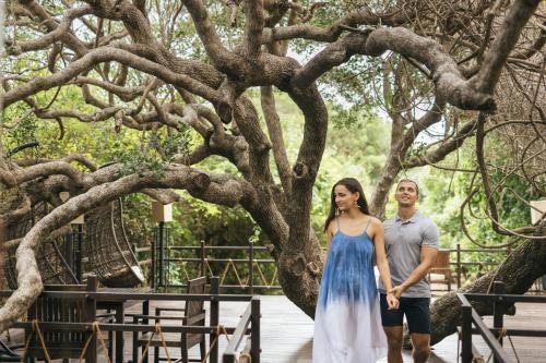 a man and a woman standing next to a tree at Uga Jungle Beach - Trincomalee in Trincomalee