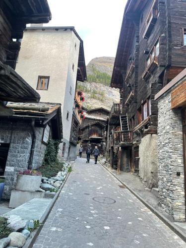 two people walking down a street between buildings at Im alten Dorfteil von Zermatt in Zermatt
