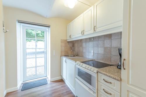 a kitchen with white cabinets and a sink and a window at Bramslevgaard in Hobro