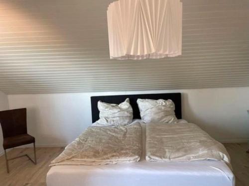 a bed with white sheets and pillows in a room at Ferienwohnung mit Seeblick in Hagnau