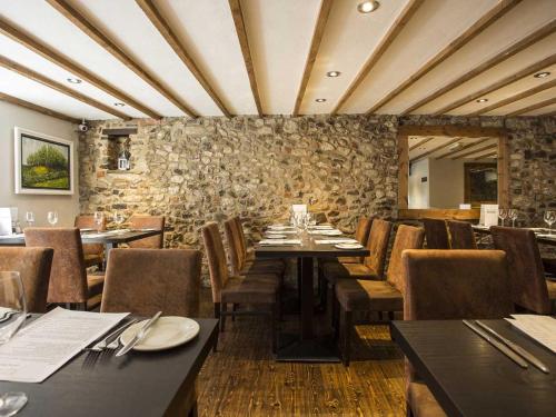 un restaurant avec des tables et des chaises et un mur en pierre dans l'établissement Bath House Hotel, à Chard
