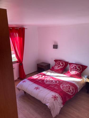 Un dormitorio con una cama con almohadas rojas y una ventana en Location appartement 4 couchages en rez de jardin, en La Cabanasse
