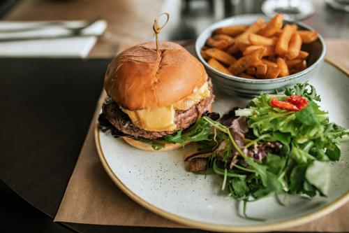 a plate with a hamburger and a salad and french fries at B&B HOTEL Lyon Nord 4 étoiles in Dardilly