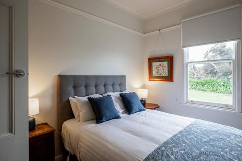 sypialnia z łóżkiem z niebieskimi poduszkami i oknem w obiekcie Bridport Beach House w mieście Bridport