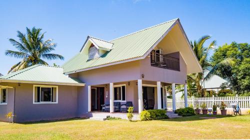 a house with a white fence and palm trees at The Garden Villas - La Digue in La Digue