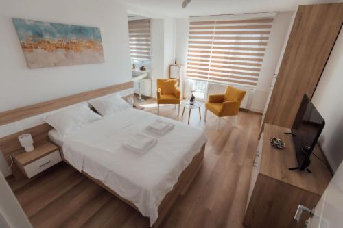 a bedroom with a white bed and a living room at La Casa M in Vršac