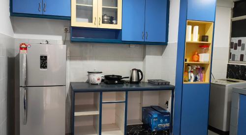 a kitchen with blue cabinets and a counter with a refrigerator at Cozzzzy Two Next to Axiata Arena, Bukit Jalil in Kuala Lumpur