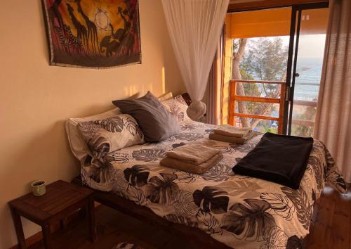 ein Bett mit Kissen darauf in einem Zimmer mit Fenster in der Unterkunft Bamboo Room in Ponta do Ouro
