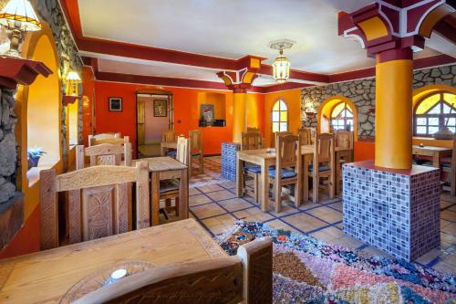 comedor con paredes de color naranja y mesas y sillas de madera en Zaratoustra en Imlil