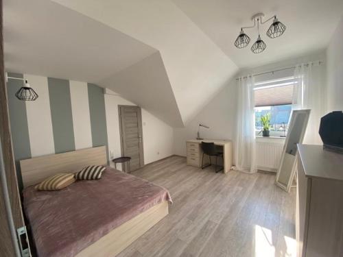 a bedroom with a bed and a desk and a window at Apartament Chopina in Suwałki