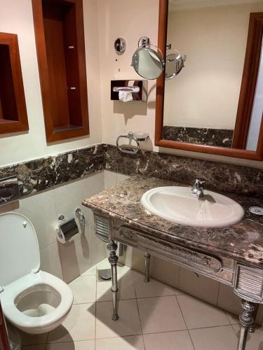 ein Badezimmer mit einem Waschbecken, einem WC und einem Spiegel in der Unterkunft Cosmopolitan hotel in Kairo