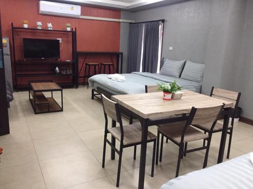 Nangnon Hill Hug Hotel في Ban Pa Muat: غرفة مع طاولة وكراسي وغرفة نوم