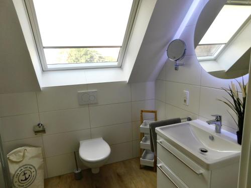 a bathroom with a sink and a toilet and a window at Grachtensteern in Greetsiel