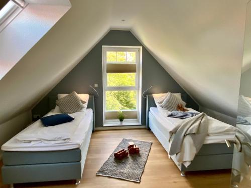 a attic bedroom with two beds and a window at Grachtensteern in Greetsiel