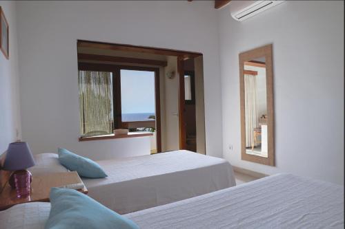 a white bedroom with two beds and a window at Hostal Marblau Ibiza in Ibiza Town