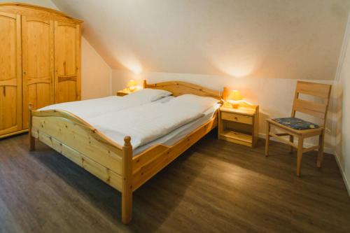 a bedroom with a large wooden bed and a chair at Hof Böhmetal in Schneverdingen