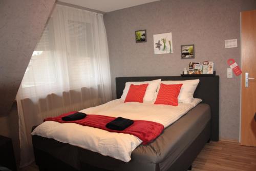 un letto con cuscini rossi sopra in una camera da letto di Diamanthaus 2 Koblenz a Coblenza