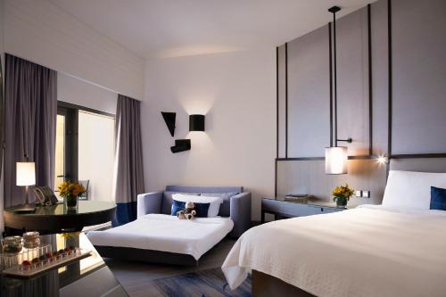 a hotel room with a bed and a chair at Amwaj Rotana, Jumeirah Beach - Dubai in Dubai