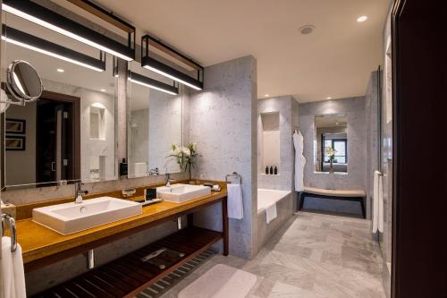 a bathroom with two sinks and a tub at Amwaj Rotana, Jumeirah Beach - Dubai in Dubai