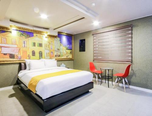 een slaapkamer met een bed en een tafel en stoelen bij Opera Motel in Yeosu