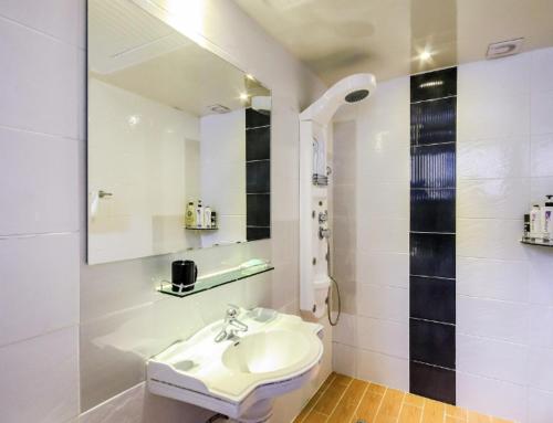 a white bathroom with a sink and a shower at Opera Motel in Yeosu