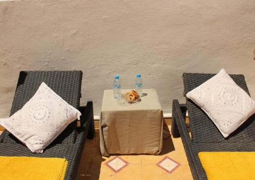 a table with two chairs and two bottles of water at Riad de charme l'Oasis d'Essaouira - Chambre Luxe in Essaouira