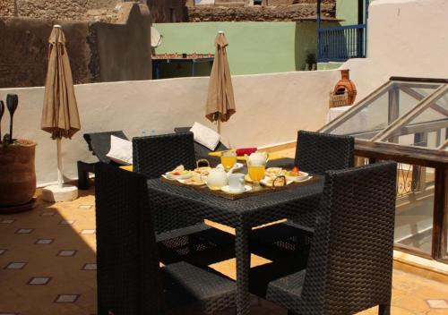 Una mesa con comida y bebidas en un balcón. en Riad de charme l'Oasis d'Essaouira - Chambre Luxe, en Essaouira