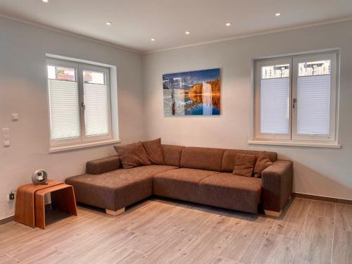 a living room with a brown couch and two windows at "Mittendrin" in Garmisch in Garmisch-Partenkirchen