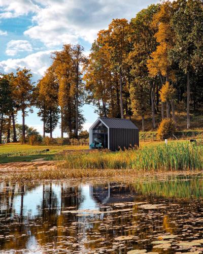 a small black building sitting next to a body of water at PullanHouse Līksma - small and cosy lakeside holiday house in Alūksne