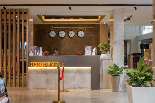 a reception desk in a building with clocks on the wall at Lazdana Hotel Bangalore in Bangalore