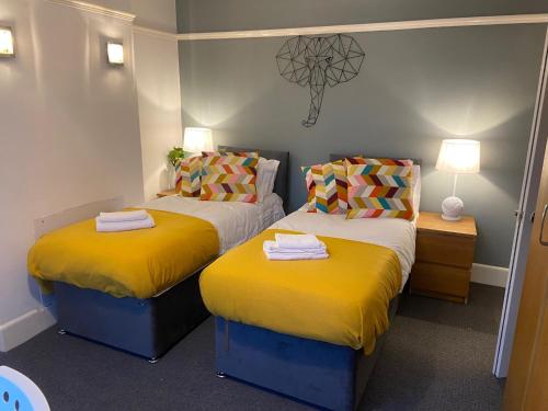 two beds in a small room with yellow sheets at Granby Grove Townhouse - Sleeps 8- 4 Bedrooms in Southampton