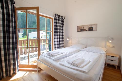 a bedroom with a bed and a large window at Tauerndorf Enzingerboden Ski in&out - Steinbock Lodges in Enzingerboden