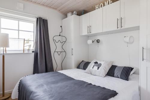 a white bedroom with a bed and a window at Cozy mobile home near sandy beach in Hammar