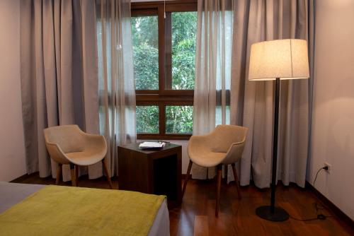 um quarto com 2 cadeiras, um candeeiro e uma janela em Hotel Tré Iguazú em Porto Iguaçu