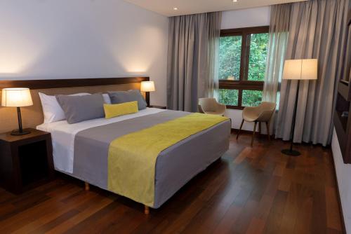 a bedroom with a large bed with a yellow blanket at Hotel Tré Iguazú in Puerto Iguazú