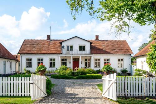 une maison blanche avec une clôture blanche dans l'établissement Svabesholms Kungsgårds B&B och Pensionat Stenshuvud, à Kivik