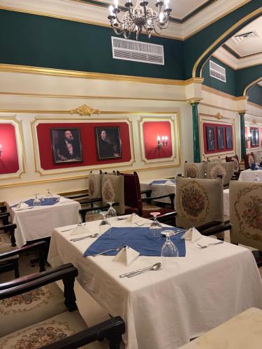 ein Esszimmer mit weißen Tischen und Stühlen sowie einem Kronleuchter in der Unterkunft Cosmopolitan hotel in Kairo