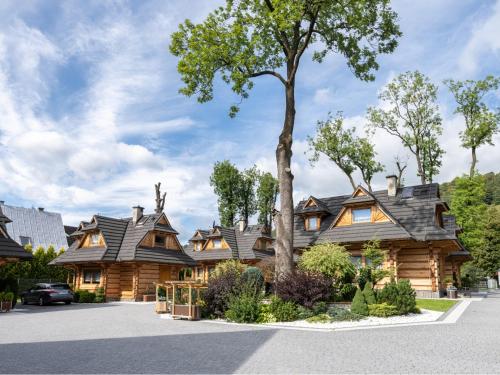 a log cabin with a tree in front of it at Osada Harenda in Zakopane