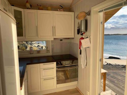 une cuisine avec des placards blancs et une vue sur l'océan. dans l'établissement Lofotparadis - nydelig hytte på unikt sted, à Valberg