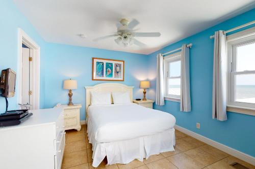 um quarto com uma cama branca e paredes azuis em Beauty And The Beach em St. George Island
