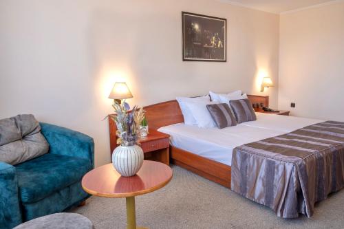 Habitación de hotel con cama y sofá azul en Hotel Orbita, en Varna