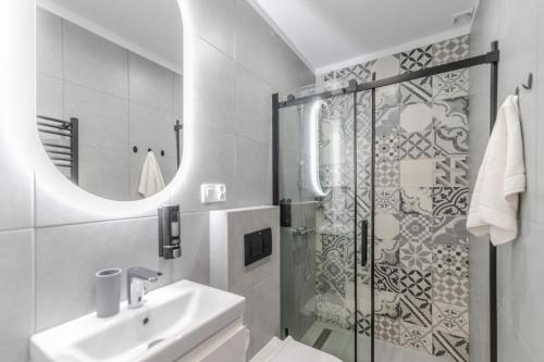 a white bathroom with a shower and a sink at Apartamenty Pod Orzechem z dużym ogrodem - Dream Apart in Ustroń
