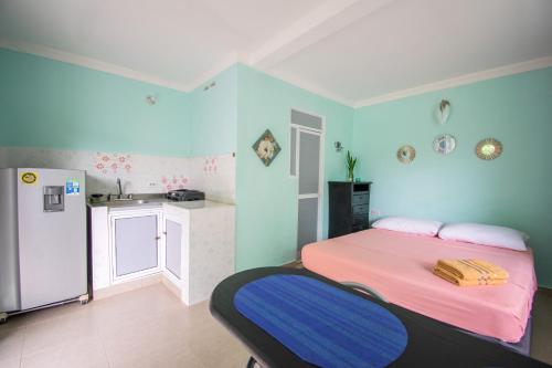 a blue room with a bed and a refrigerator at Perth House Taganga in Taganga