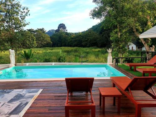 a swimming pool with two chairs and a table at Chateau de Luxi Khao Yai - ชาโตว์ เดอ ลูซี่ เขาใหญ่ in Mu Si
