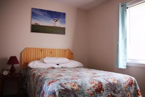 1 dormitorio con 1 cama con una foto de pájaro en la pared en Rustico Acres Cottages, en North Rustico