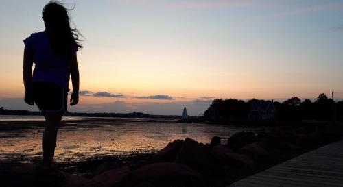 a woman standing on the beach at sunset at Rustico Acres Cottages in North Rustico